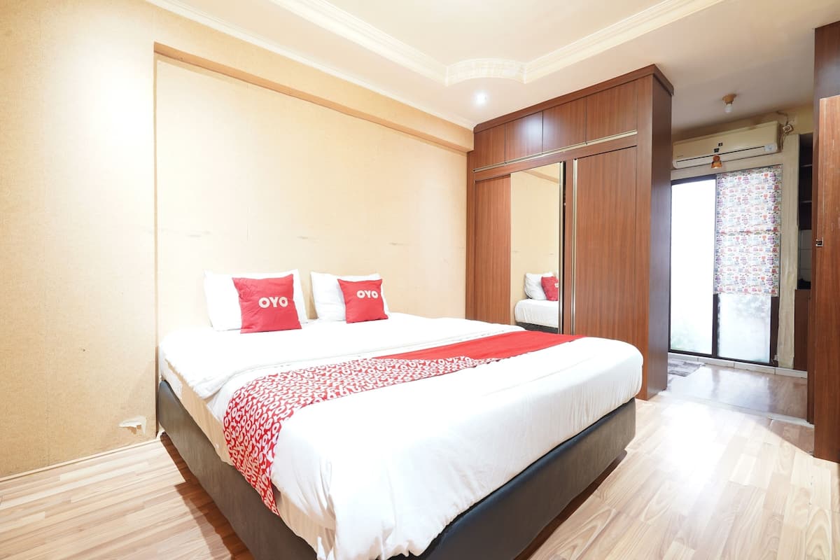 Une chambre à coucher comprenant un lit, une armoire et une porte-fenêtre coulissante donnant sur un balcon.