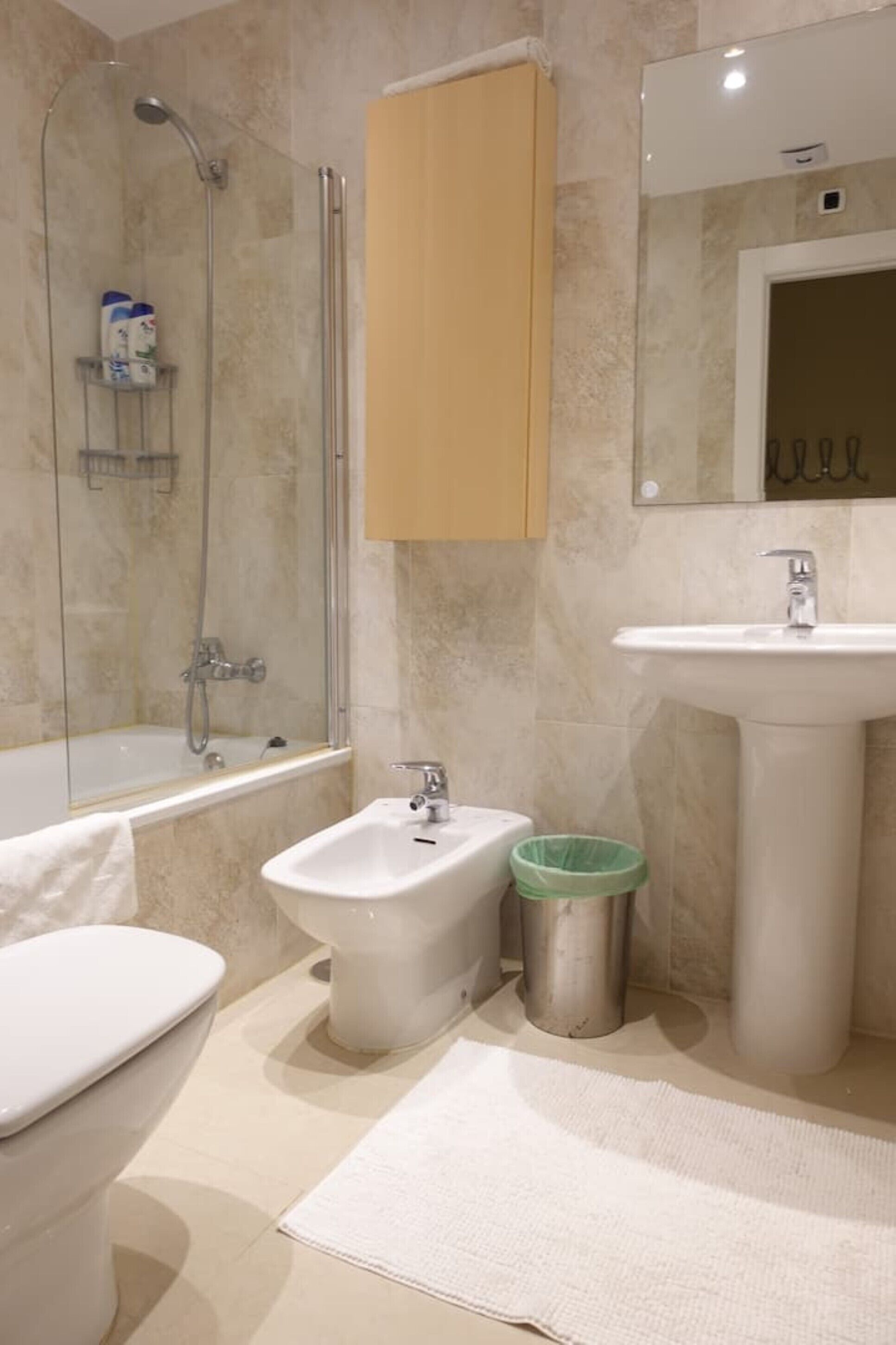 A bathroom with a bathtub, toilet, bidet, sink, and a mirror.