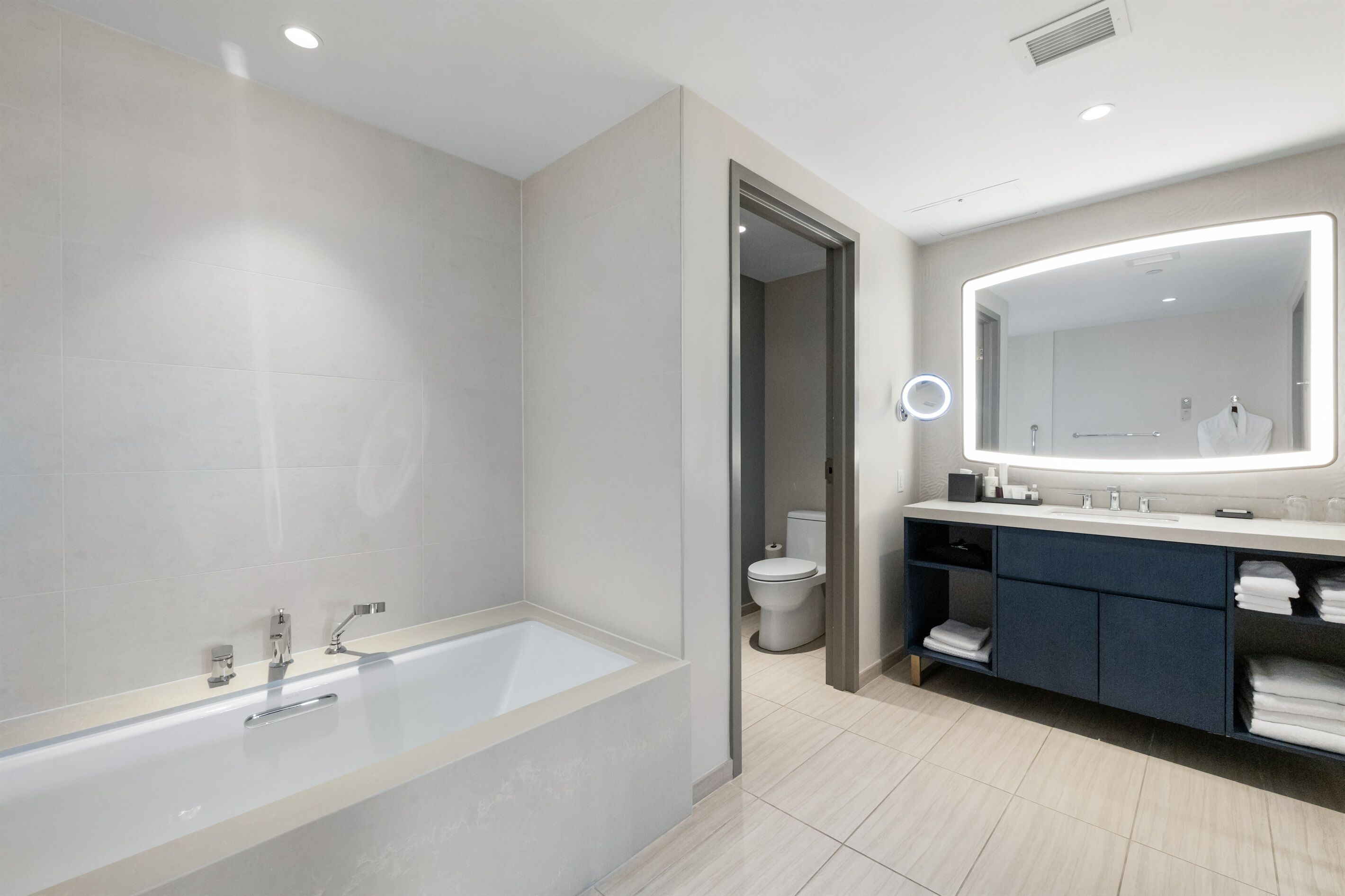 Un baño moderno con bañera, tocador con espejo y un inodoro.