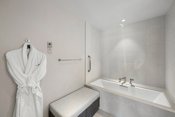 Un baño moderno con una bañera grande, un perchero para toallas y un banco.