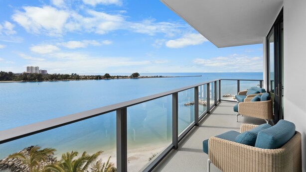 Un balcon avec des fauteuils en osier et vue sur la mer.
