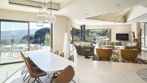 A spacious living area with a large dining table, comfortable seating, and a view of the outdoors.