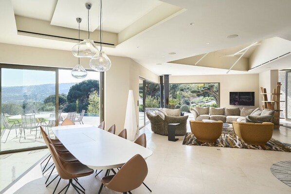 Un espace de vie spacieux comprenant une grande table à manger, des sièges confortables et une vue sur l’extérieur.