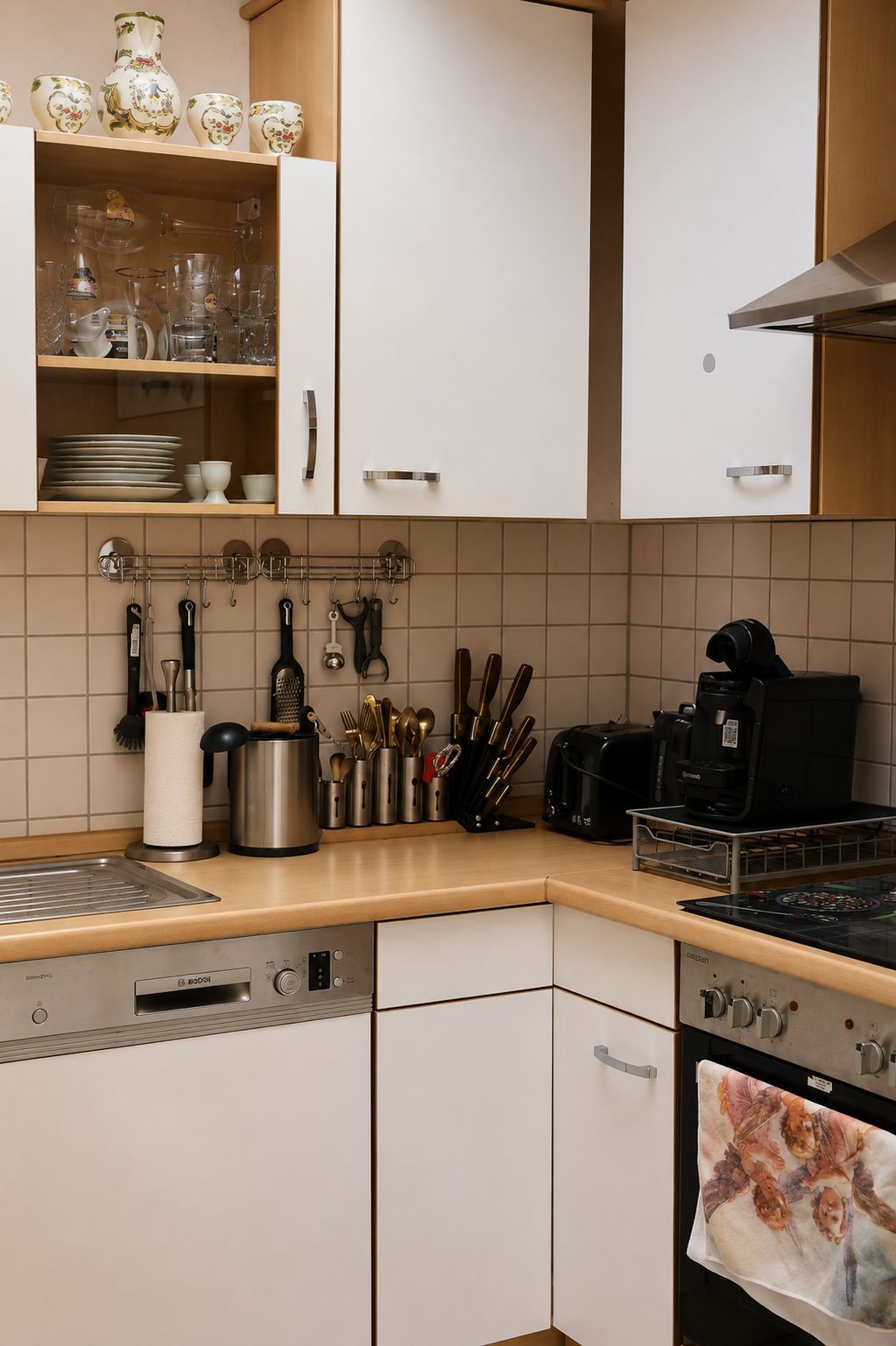 Eine Küche mit weißen Schränken, einer Kaffeemaschine, einem Toaster und einem daran hängenden Küchenutensilienhalter.