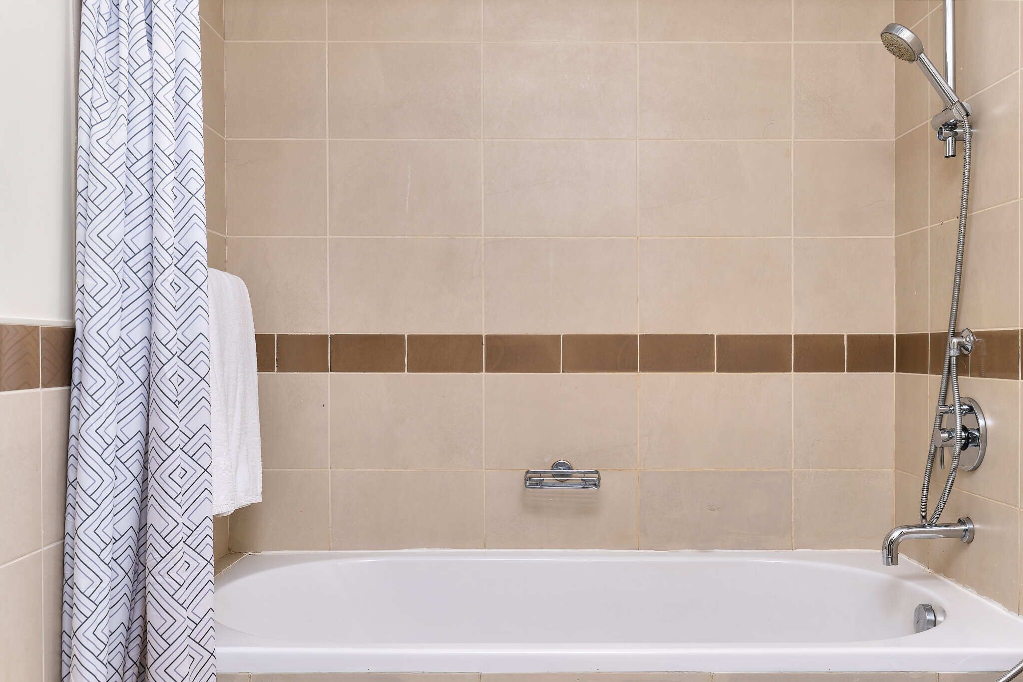 A bathroom with a bathtub, shower, and towel rack.