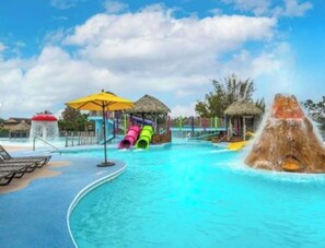 A water park with slides, a pool, and thatched-roof structures.