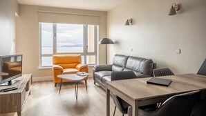 A modern living room with a large window, a sofa, a coffee table, and a TV.