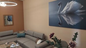A modern living room with a sectional sofa, a coffee table with decorative items, a wall-mounted mirror, and a large painting of a swan.