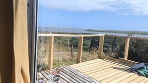 Une terrasse en bois offrant une vue sur un lac et sur la terre ferme, qui s’étend au loin.