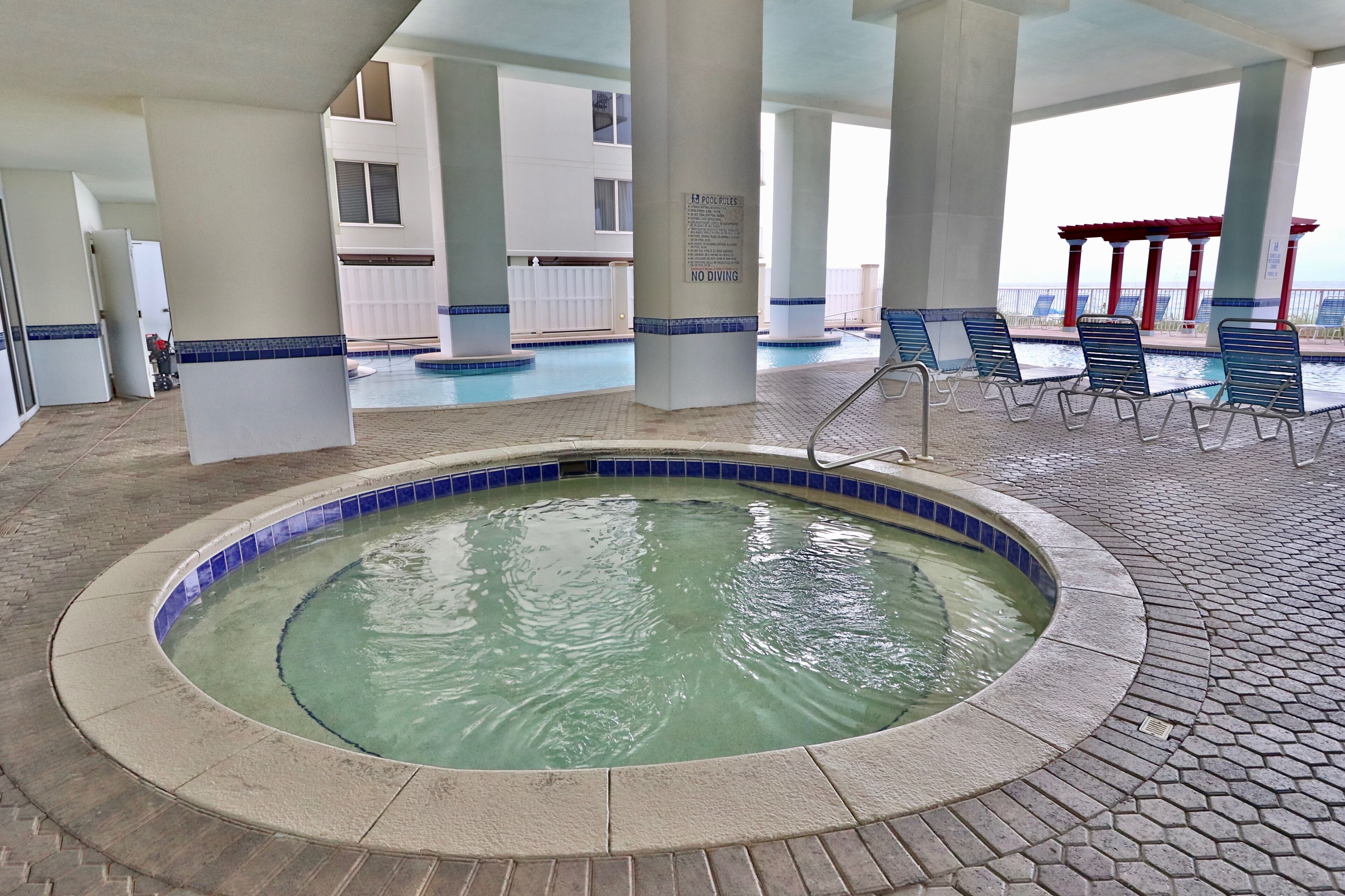 A hot tub area with a pool, lounge chairs, and a no diving sign.