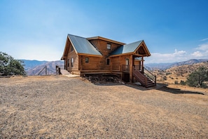 A wooden cabin with a metal roof, a porch, and a staircase leading to the entrance. - 4 Kings Log Cabin 150 Acres Spectacular Views (Three Rivers)