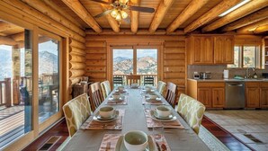 A log cabin with a dining area, kitchen, and large windows. - 4 Kings Log Cabin 150 Acres Spectacular Views (Three Rivers)