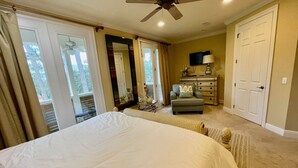 Quarto com uma cama grande, um ventilador de teto, cômoda e televisão.