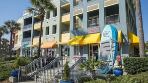 Um hotel com vários andares, varandas, um restaurante visível chamado 'YOLO' e uma exposição de pranchas de surf na parte externa.