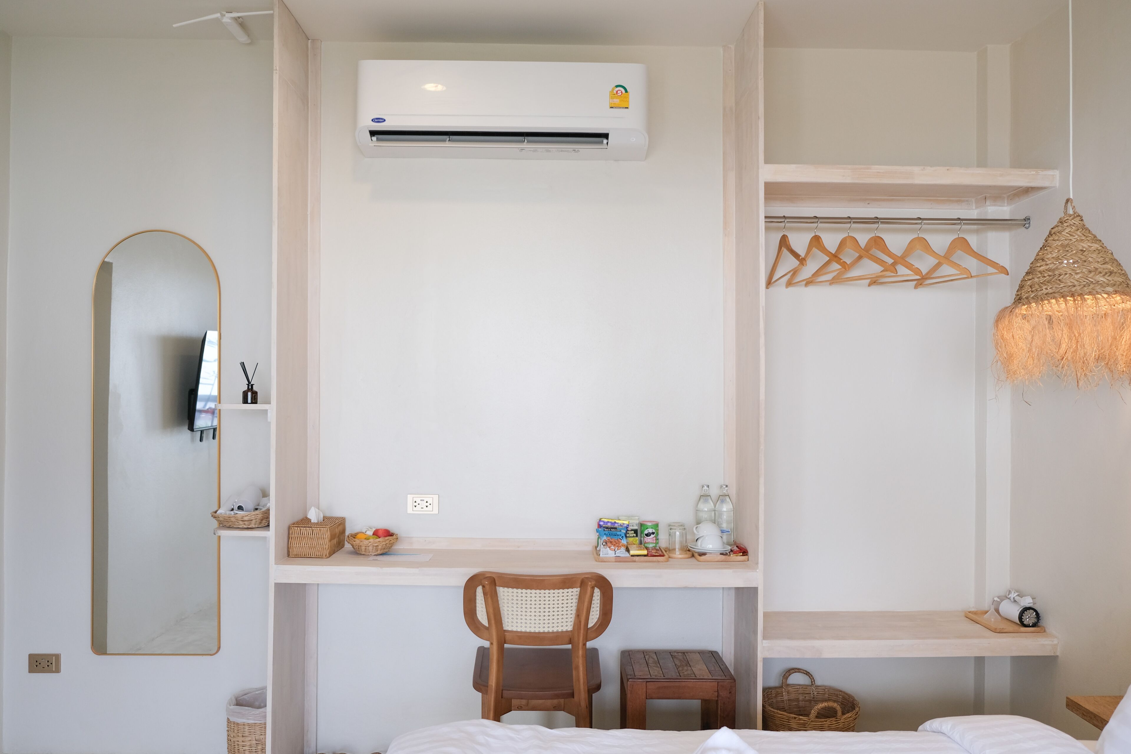 Ein Hotelzimmer mit Bett, Schreibtisch mit Stuhl, Spiegel, Klimaanlage und einer Pendelleuchte.