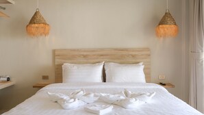 A neatly made bed with white linens and towels, two bedside tables with a remote control, and two hanging woven light fixtures. - Nymph Hideout (Ko Pha-ngan)