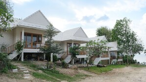 A row of white buildings with steep roofs, wooden balconies, and a dirt path leading to the entrance. - Nymph Hideout (Ko Pha-ngan)
