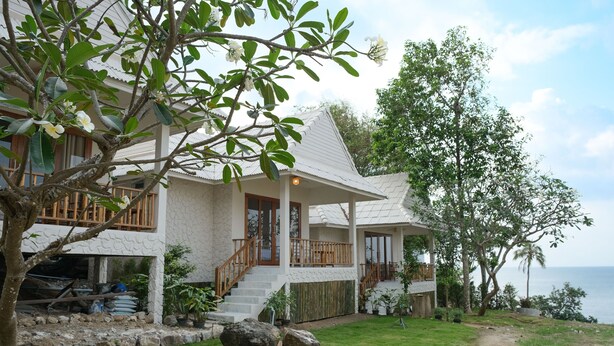 A two-story house with a white exterior, a wooden deck, and a view of the sea. - Nymph Hideout (Ko Pha-ngan)