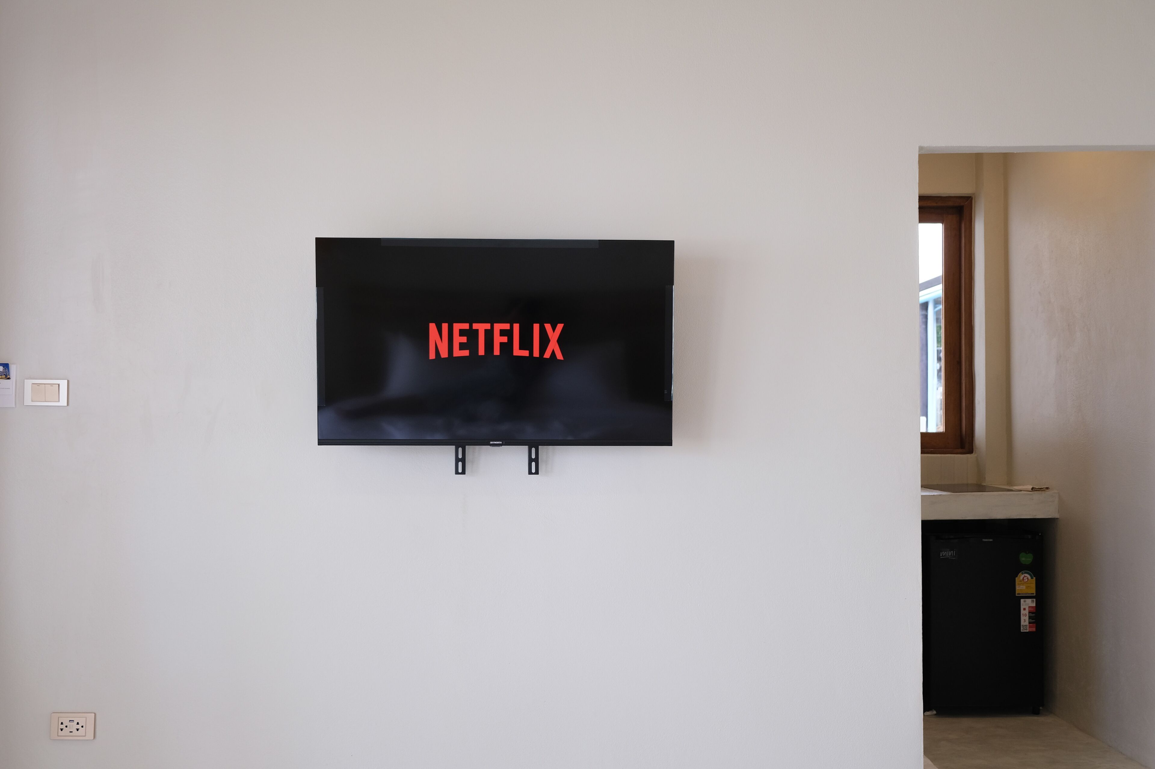 A flat-screen TV mounted on a white wall with the word "NETFLIX" in red letters.