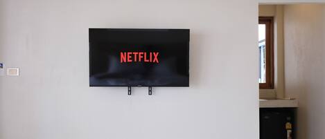 A flat-screen TV mounted on a white wall with the word "NETFLIX" in red letters.