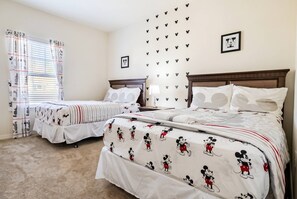 A hotel room with two beds, a window with curtains, wall decals, and a framed picture.