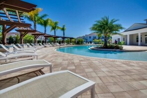 Un área de piscina con sillas de descanso y una pérgola.