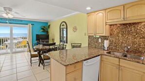 A kitchen with granite countertops, wooden cabinets, and a built-in dishwasher. - 🌞 South Beach Condo #503 Gulf Front Serenity with Balcony on Treasure Island (Treasure Island)