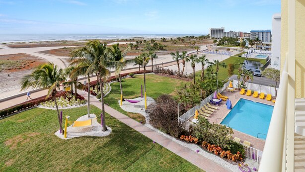 A resort with a pool, palm trees, and a view of the beach. - 🌞 South Beach Condo #503 Gulf Front Serenity with Balcony on Treasure Island (Treasure Island)