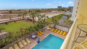A hotel pool area with a view of the beach and ocean.