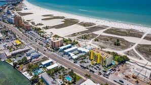 An aerial view of a coastal area with a beach, hotels, and a marina.