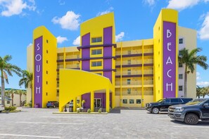 A multi-story hotel with a vibrant yellow and purple facade, featuring balconies and a central entrance with a yellow canopy. - 🌅 South Beach Condo #408  Spacious Gulf Front Escape for Families & Friends (Treasure Island)