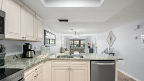 Une cuisine moderne avec des meubles de couleur claire, un plan de travail en granit et un lave-vaisselle.
