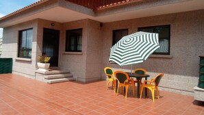 A house with a patio, a table, and four chairs. - Apartamento EN EL Rural CON Terraza EN Sanxenxo, Cerca DEL MAR (Rebel- Vilalonga, Sanxenxo)