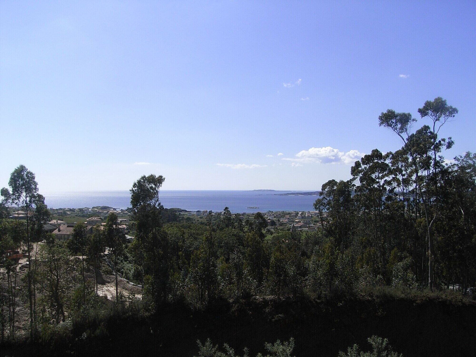 A coastal landscape with a view of the sea and a town in the distance.