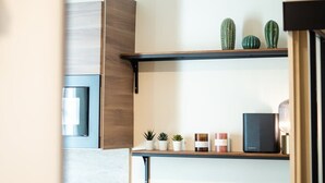 Une cuisine moderne avec des meubles de rangement en bois, un plan de travail et une étagère ornée d’objets décoratifs.