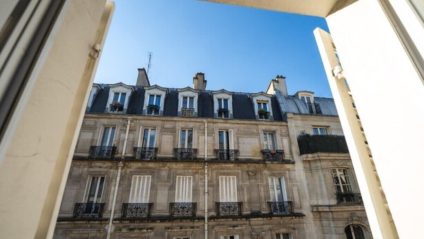 Un immeuble à plusieurs étages, de style architectural classique, caractérisé par des fenêtres et des balcons disposés de manière symétrique.