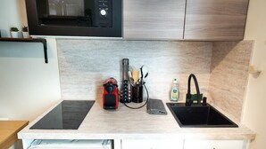 Une cuisine équipée d’un évier à deux bacs, d’un four à micro-ondes et d’une machine à café.