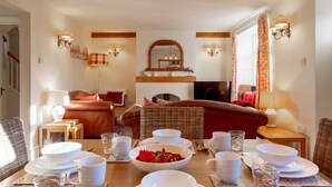 Un coin repas avec une table mise pour le repas, un canapé et un téléviseur en arrière-plan.