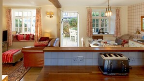 Une cuisine chaleureuse avec un plan de travail en bois, un grille-pain et un coin repas comprenant une table et des chaises.