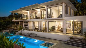 Et moderne hus i to etager med swimmingpool, store vinduer og et veloplyst interiør.