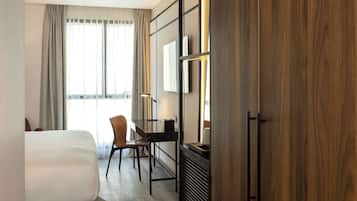 A hotel room with a bed, a desk, a chair, and a wardrobe.