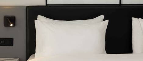 A neatly made bed with white linens and a black headboard.