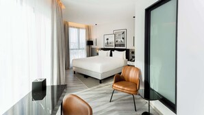 A modern hotel room with a large bed, a leather armchair, a small table, and a large window. - Radisson Hotel Tunis, City Center (Tunis)