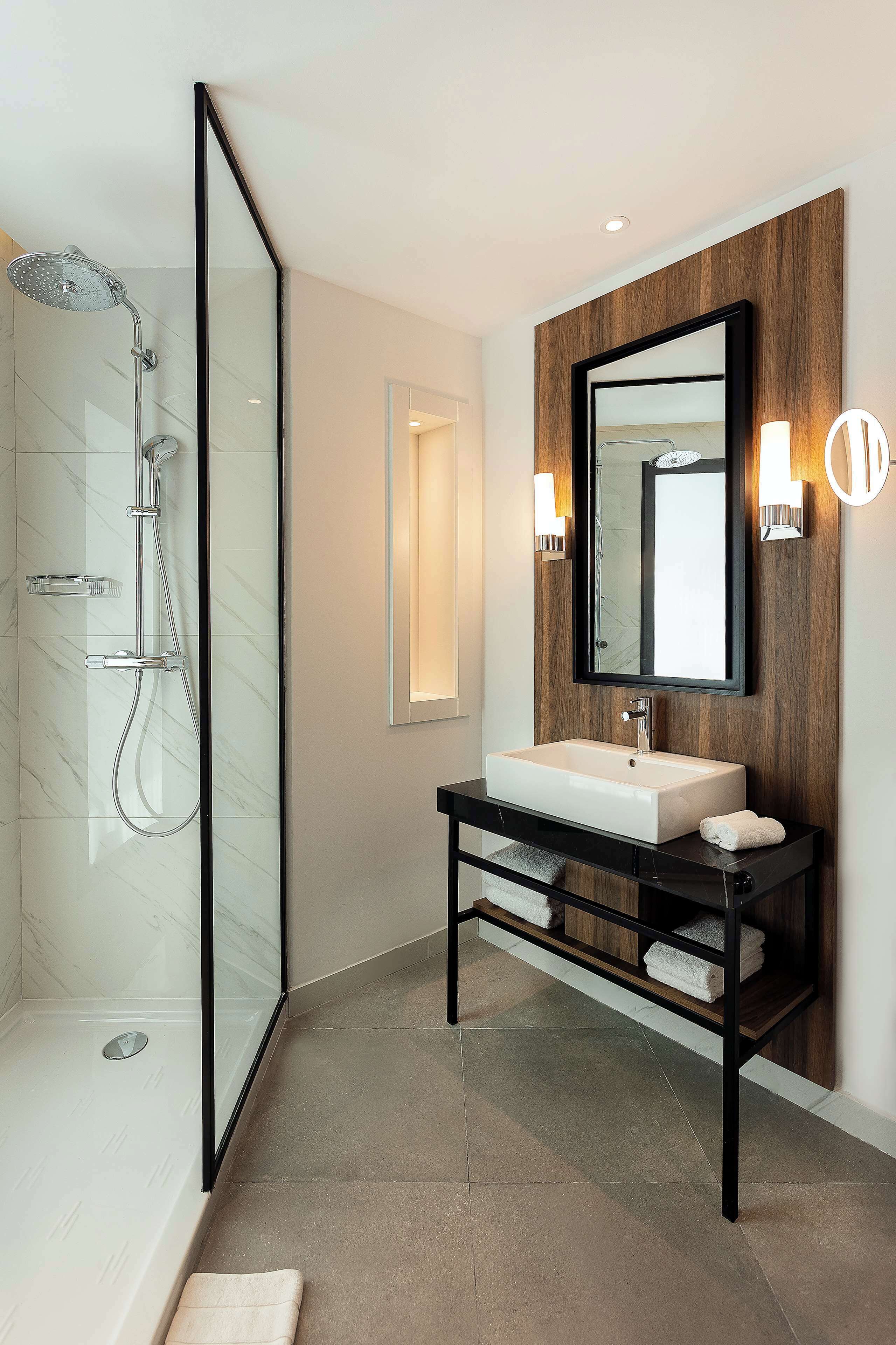 Une salle de bain moderne avec une douche à parois de verre, un lavabo blanc et un meuble-lavabo en bois.