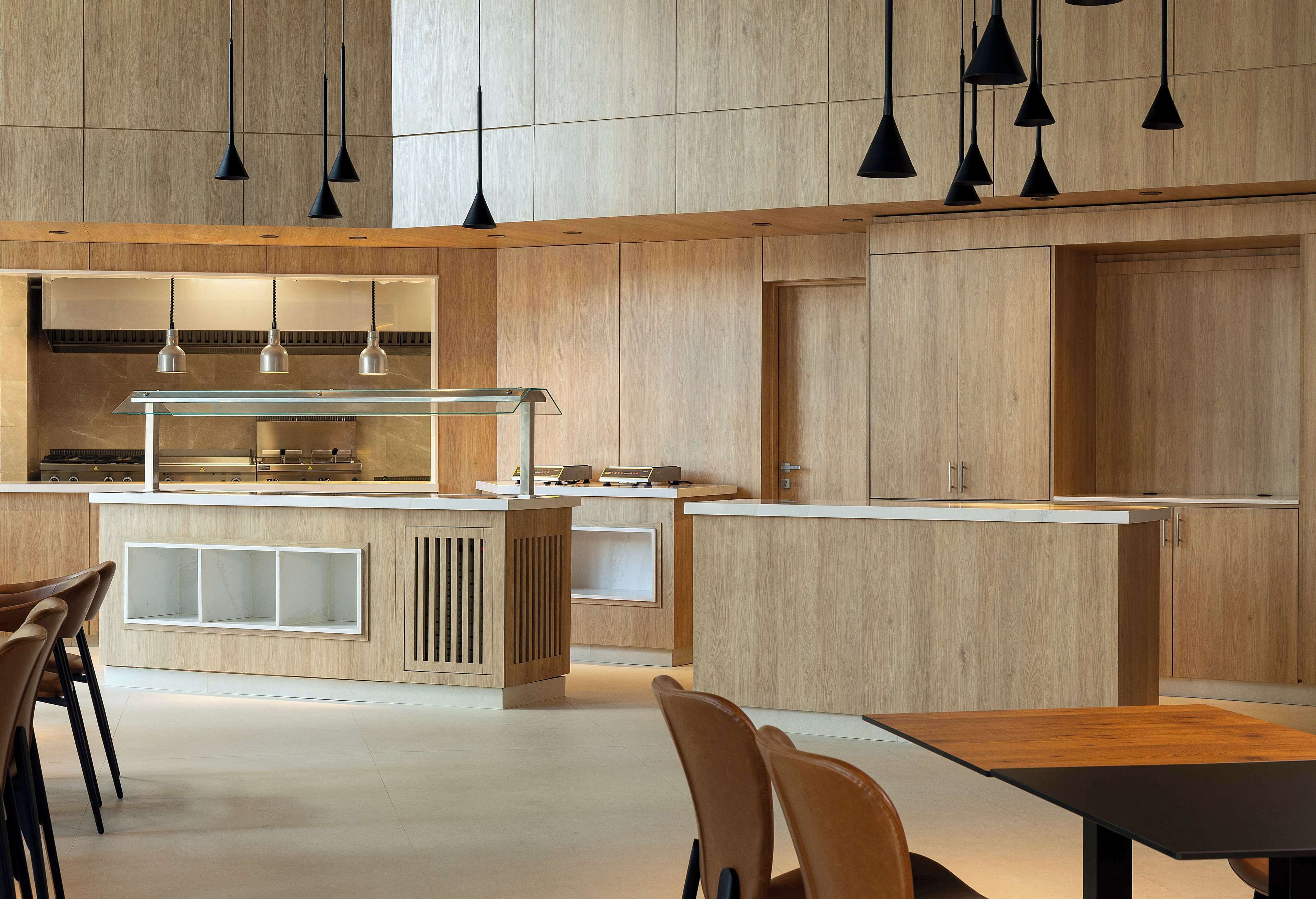 A modern kitchen with wooden cabinets, a central island with a glass top, and pendant lighting.
