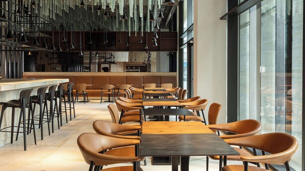 A modern restaurant with high ceilings, hanging pendant lights, and a mix of bar and dining tables. - Radisson Hotel Tunis, City Center (Tunis)