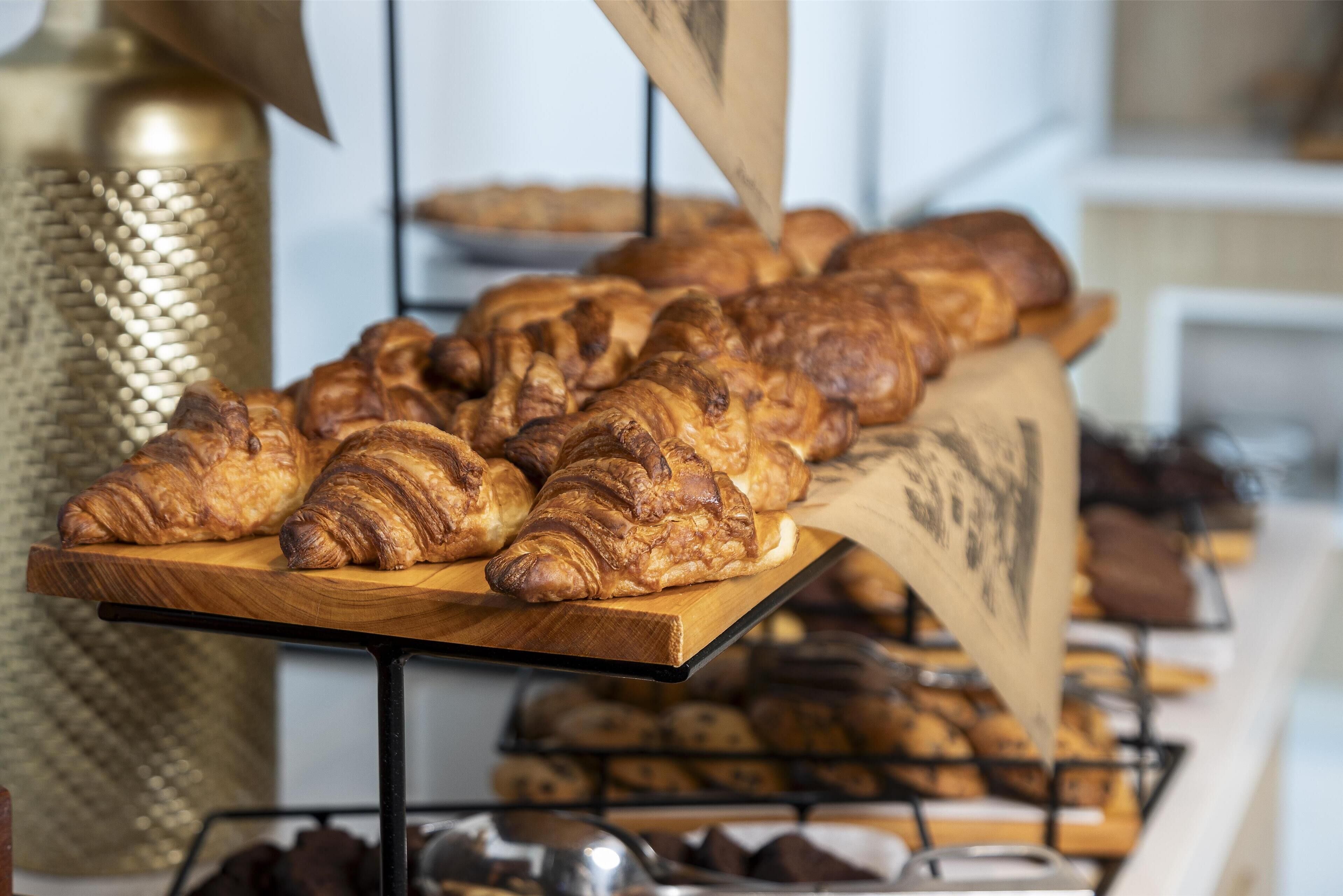 Une variété de pâtisseries présentées sur une planche en bois, avec un récipient en métal décoratif en arrière-plan.