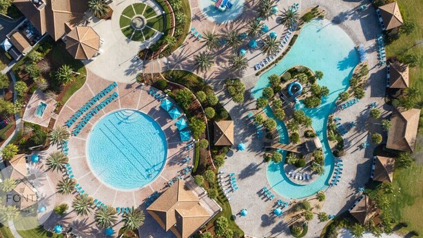 An aerial view of a resort with multiple swimming pools, sun loungers, and palm trees. - 1028L Resort 4BR Pool House FREE Grill by Disney (Kissimmee)