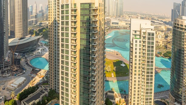 Un edificio de gran altura llamado Ramada, con múltiples balcones, una piscina y edificios modernos circundantes.