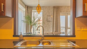 Una cocina con un lavamanos doble, una lámpara colgante y vistas al exterior a través de una ventana.
